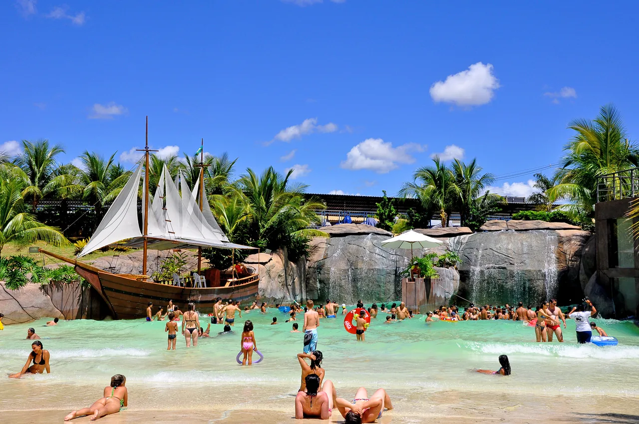 Piscina de ondas com praia artificial cheia de visitantes no diRoma Acqua Park