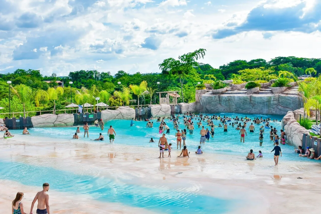 Piscina de ondas com praia artificial cheia de visitantes no Kawana Park